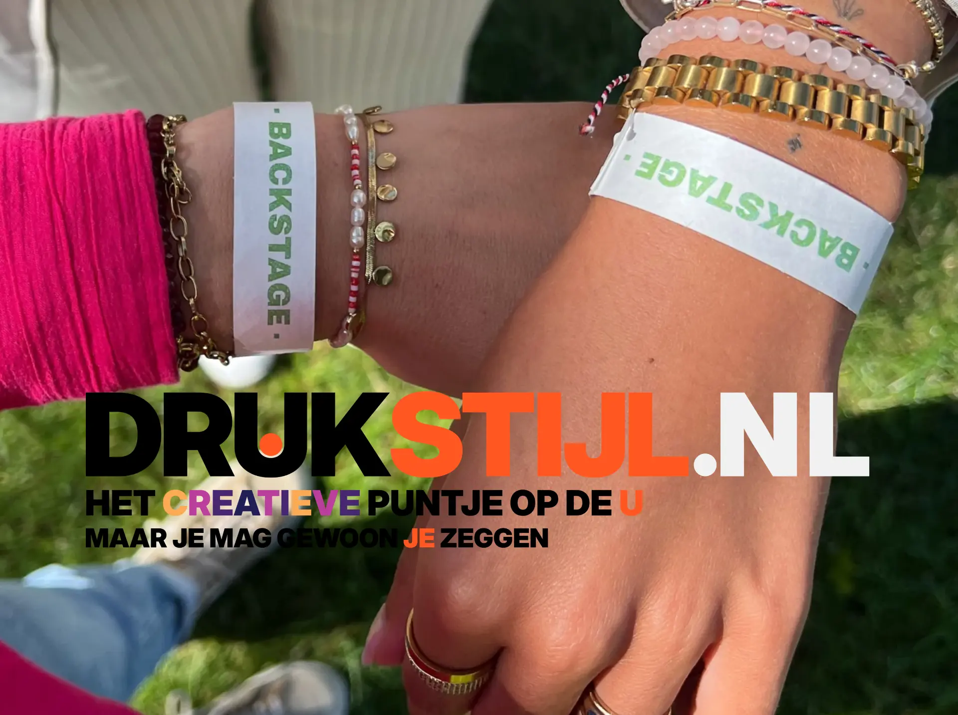 Twee armen met witte polsbandjes met groene BACKSTAGE-bedrukking
