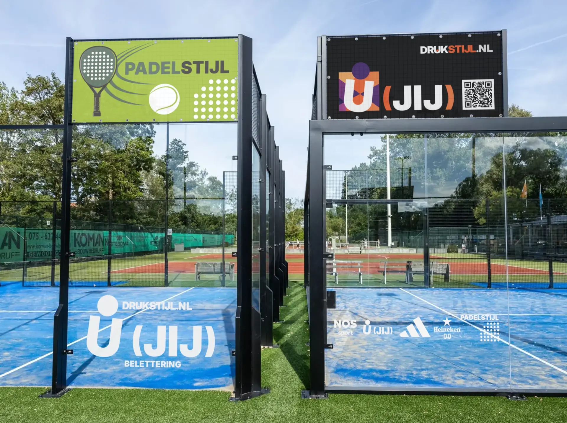 Padelbaan met DRUKSTIJL-belettering en sponsorborden